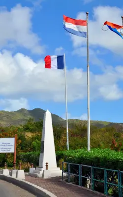 French and Dutch flags flying at the St Martin–Sint Maarten border monument - historic things to do in St Martin / St Maarten