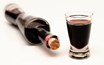 Bottle and shot glass of dark guavaberry liqueur, a traditional Caribbean spirit.
