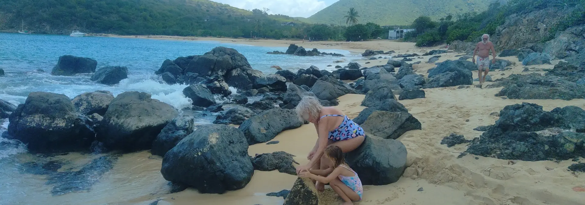 Rocky shoreline and family exploring quiet beach at Happy Bay, St Martin