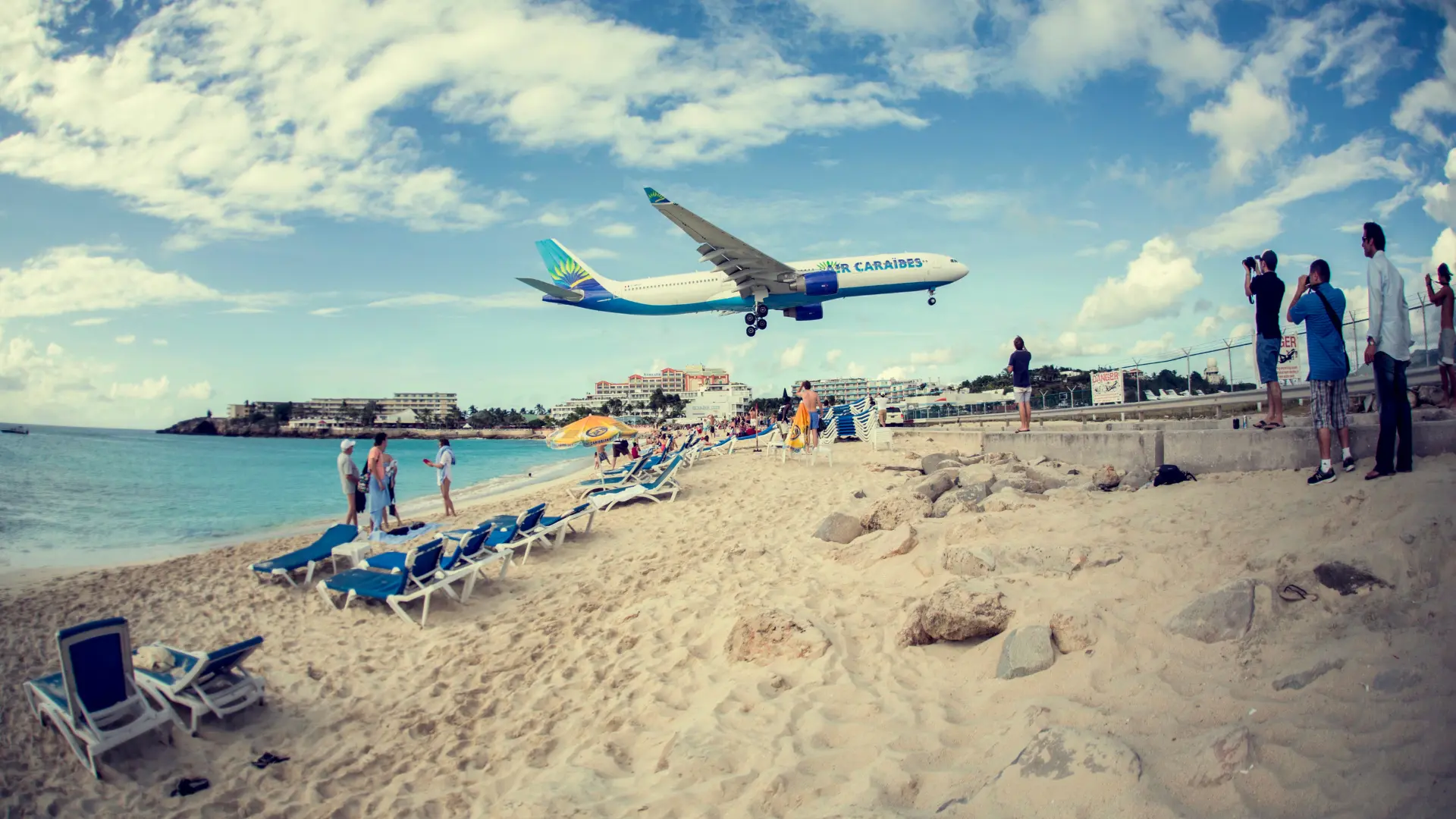 air caraibes flight landing low over maho beach with people in sand at sint maarten. one of the best things to do in st martin and st maarten