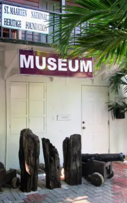 Exterior of the St. Maarten National Heritage Museum in Philipsburg, with wooden artifacts displayed near the entrance.