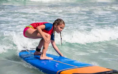 Young girl learning to surf in gentle waves at Le Galion Beach, St Martin. Family friendly Things to do in St Martin / St Maarten