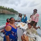 All-women group dressed for a day at sea, gathered on a private boat with a resort visible in the background of St Maarten.