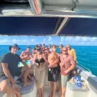 Multi-generational family posing together on a private boat near a calm green beach in Sint Maarten.