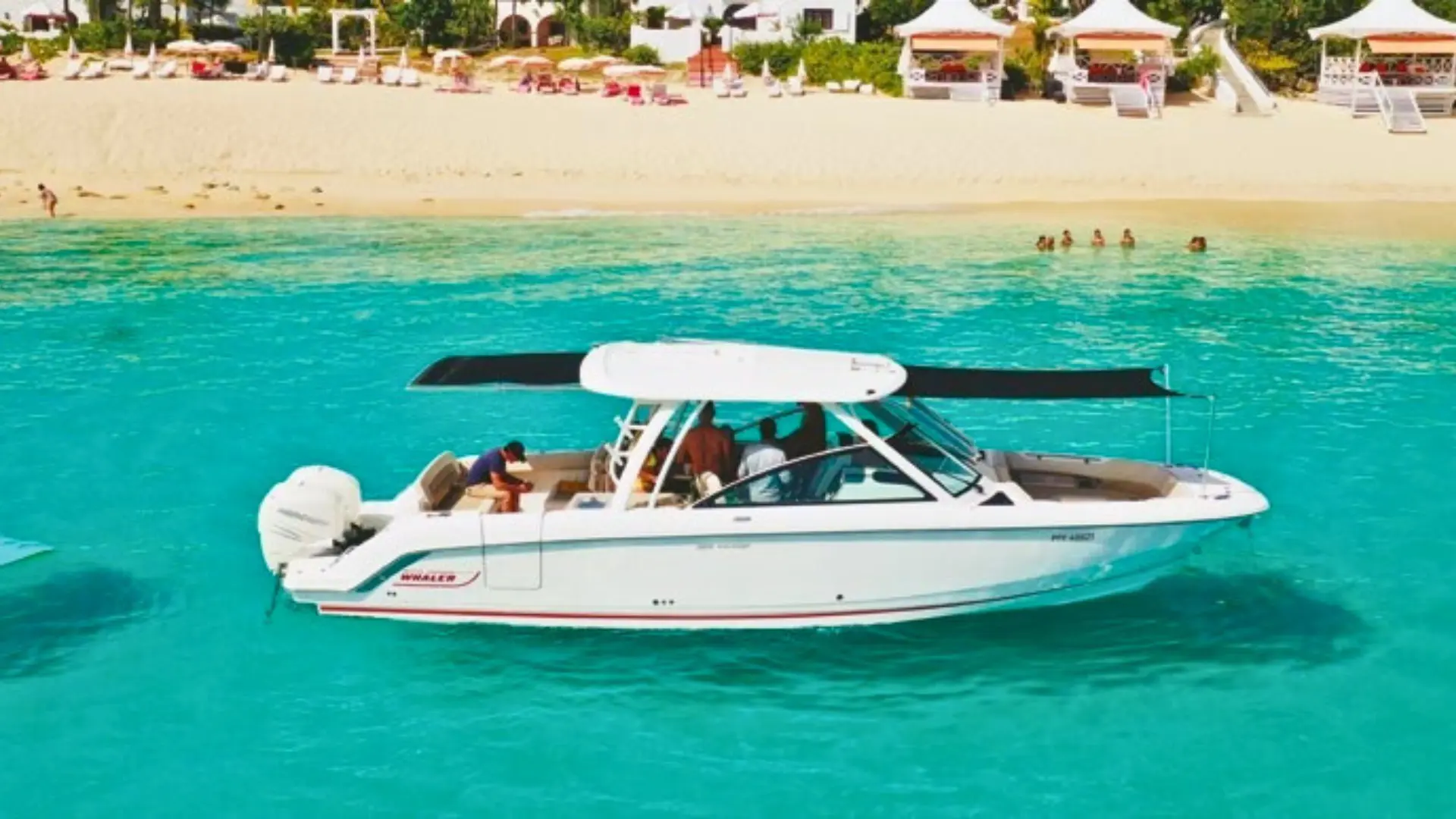 Private boat anchored off a white-sand beach in St Martin with crystal-clear turquoise water