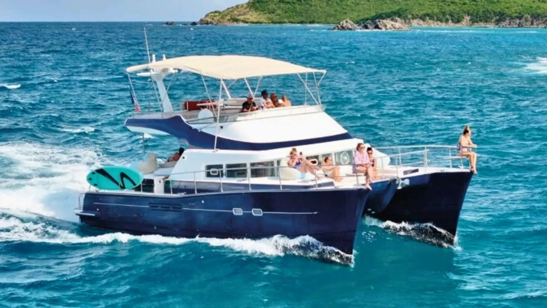 Luxury power catamaran cruising off the coast of St Martin with guests relaxing on the bow