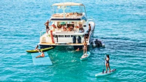 Private motor catamaran anchored with guests swimming and paddleboarding in turquoise St Martin water