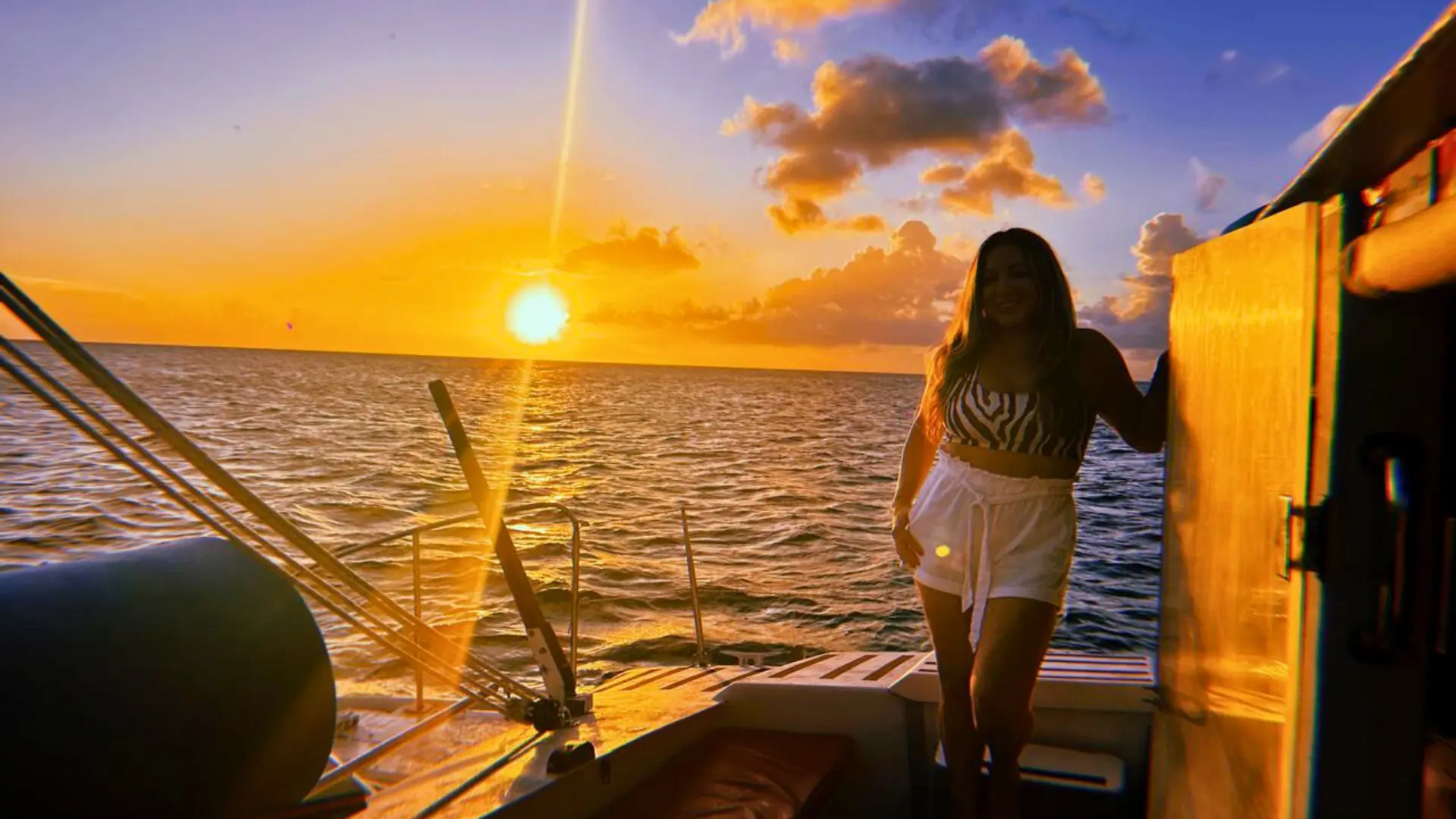 Golden Caribbean sunset viewed from a catamaran deck with guest admiring the horizon