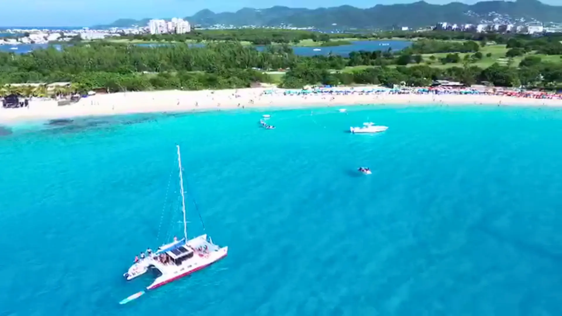 Aerial view of a red-and-white catamaran anchored off Maho Beach in turquoise waters of St Maarten