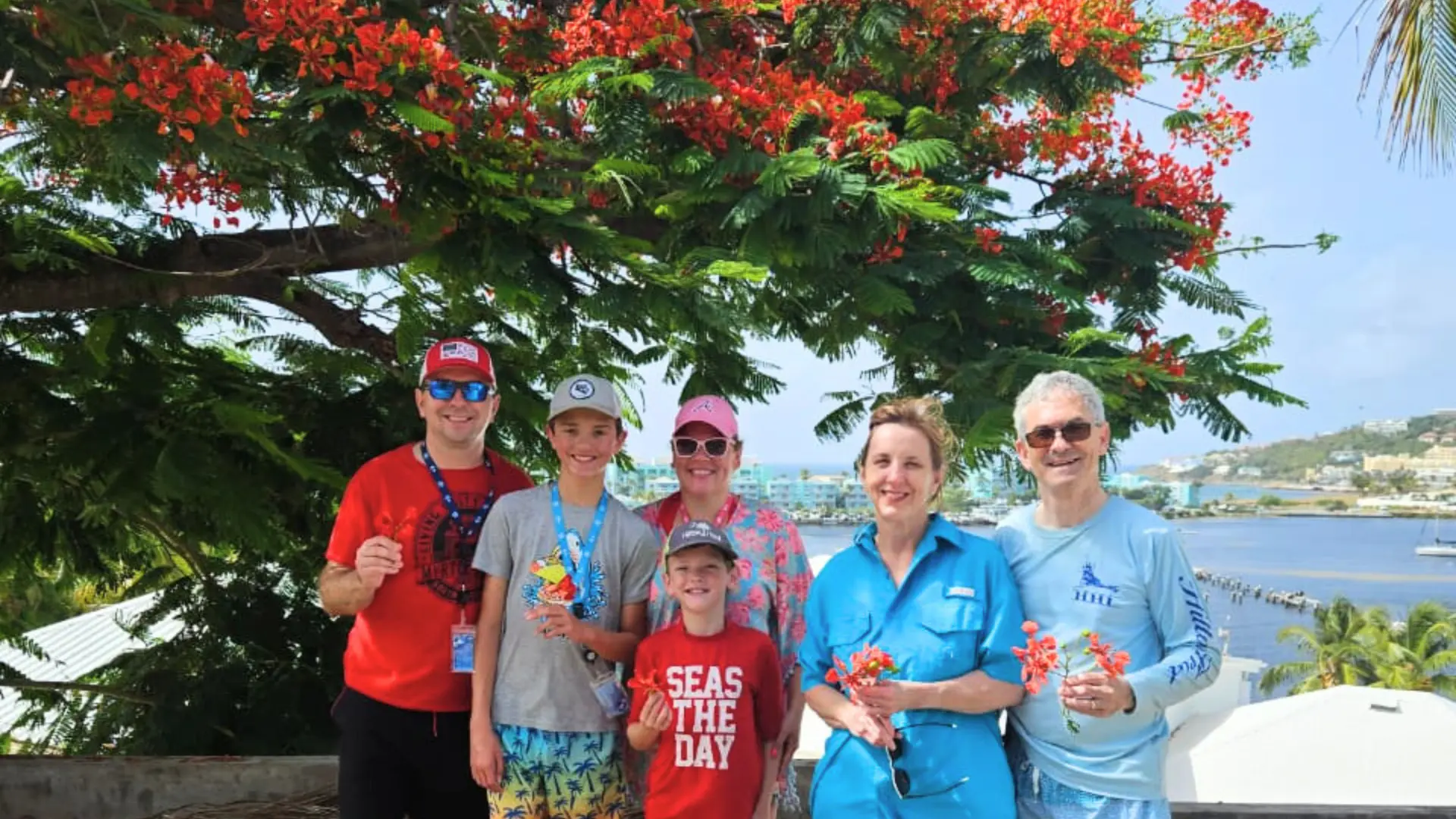Family standing under a flamboyant tree with views over Philipsburg during a St Maarten sightseeing tour