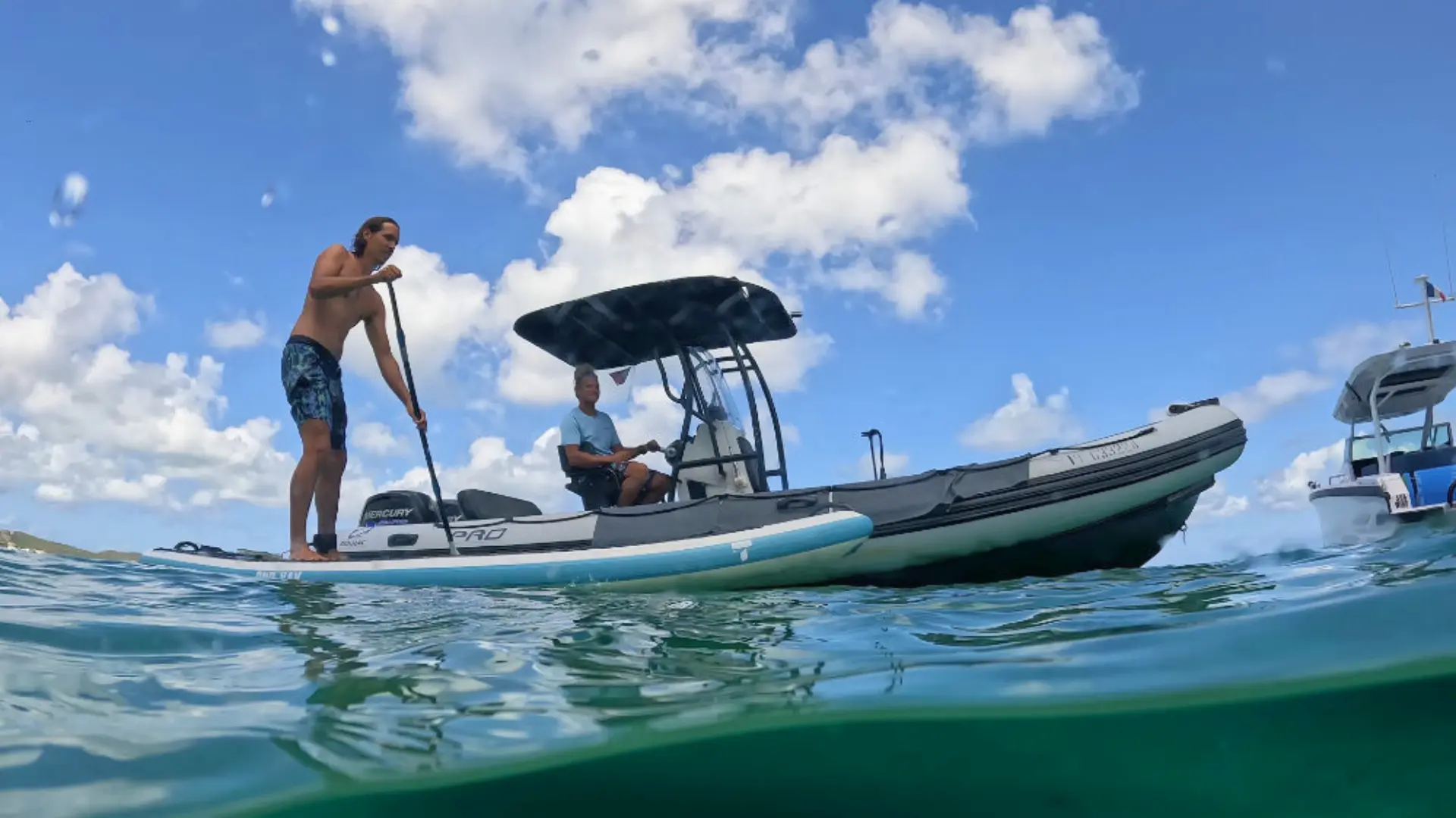 Paddleboarder gliding beside a Zodiac support boat in the clear waters of St Martin