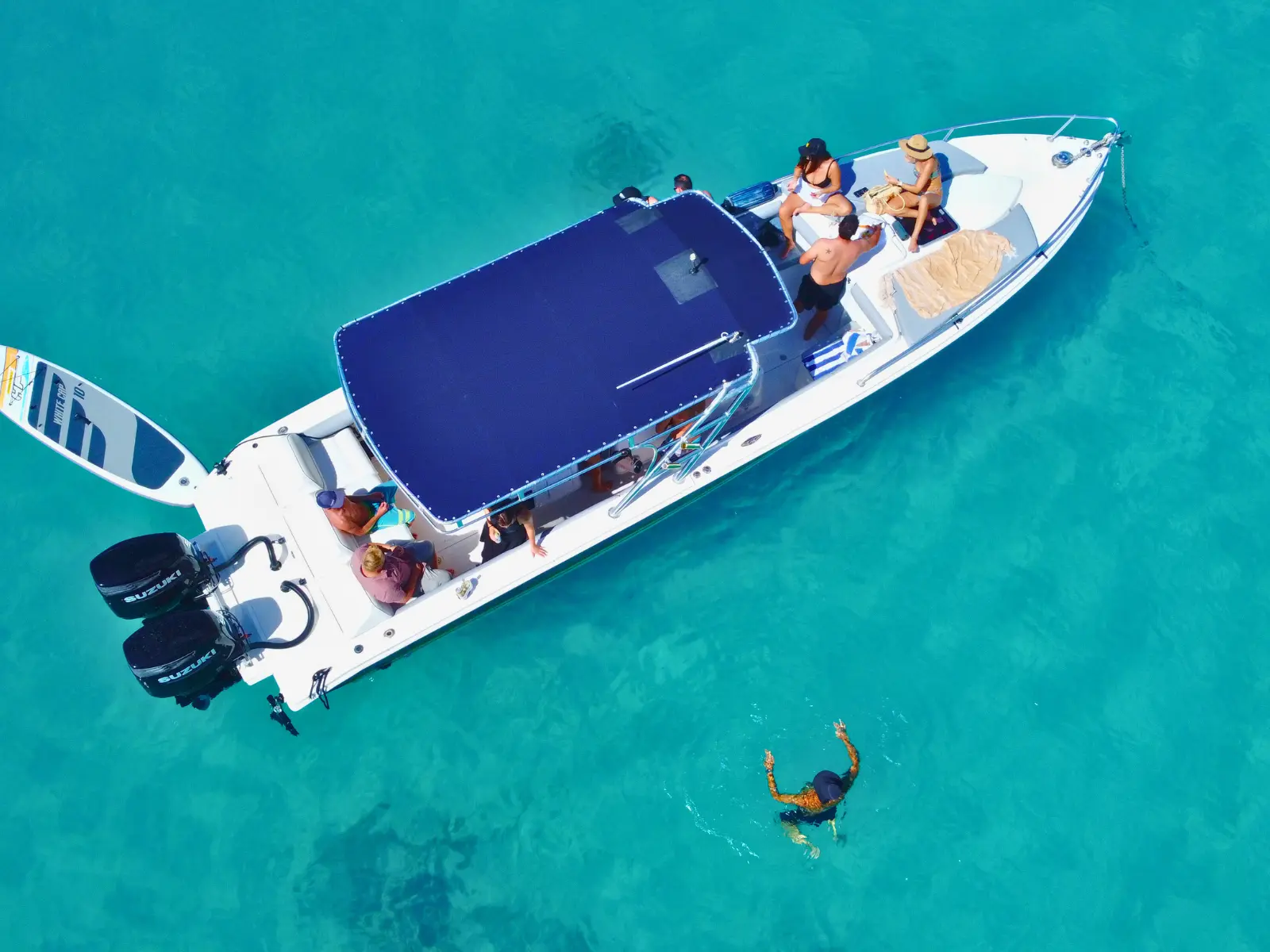 Aerial view of a private boat charter in St Barts with a guest swimming beside the boat in clear turquoise water