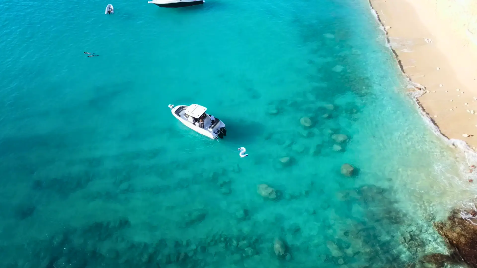 Drone view of white speedboat anchored beside sandy beach in Anguilla