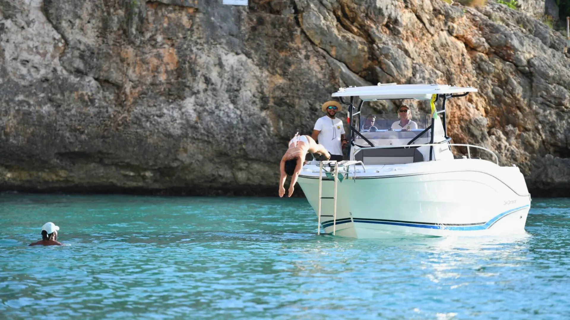 Guest diving from private boat into turquoise water at Little Bay Anguilla