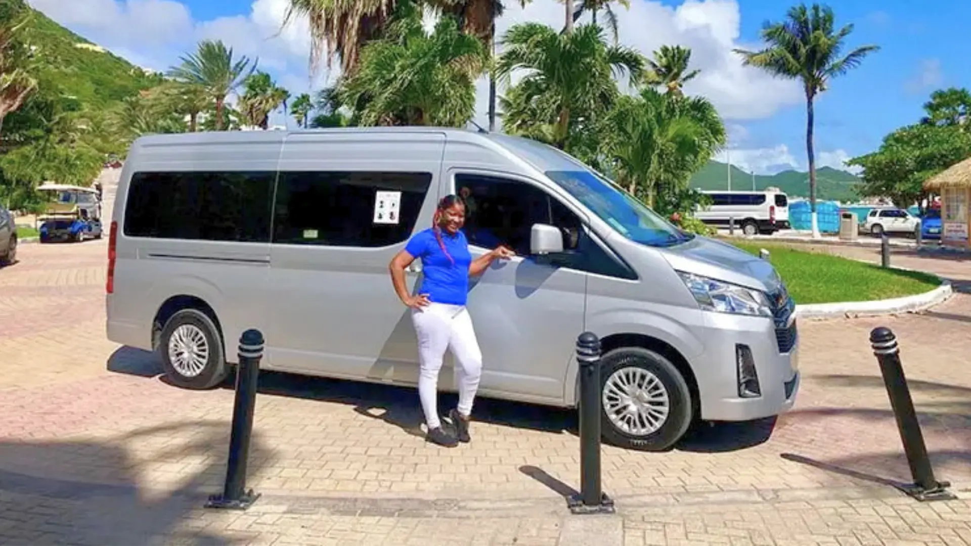 Professional island tour driver standing beside air-conditioned passenger van in St Maarten