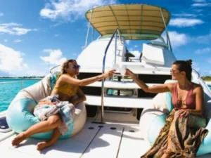 Two women relaxing on catamaran flybridge with drinks in turquoise Caribbean waters