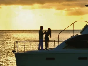 Couple standing on luxury yacht deck at sunset in the Caribbean