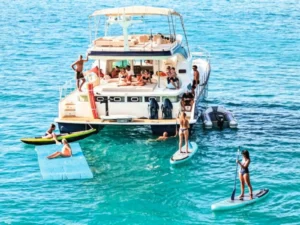 Rear view of a power catamaran with guests swimming, paddleboarding, and relaxing in the water
