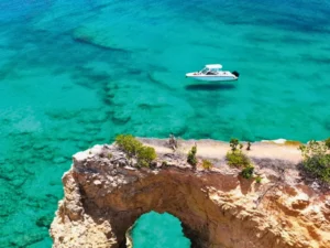 Private boat anchored near rocky coastal arch in St Martin