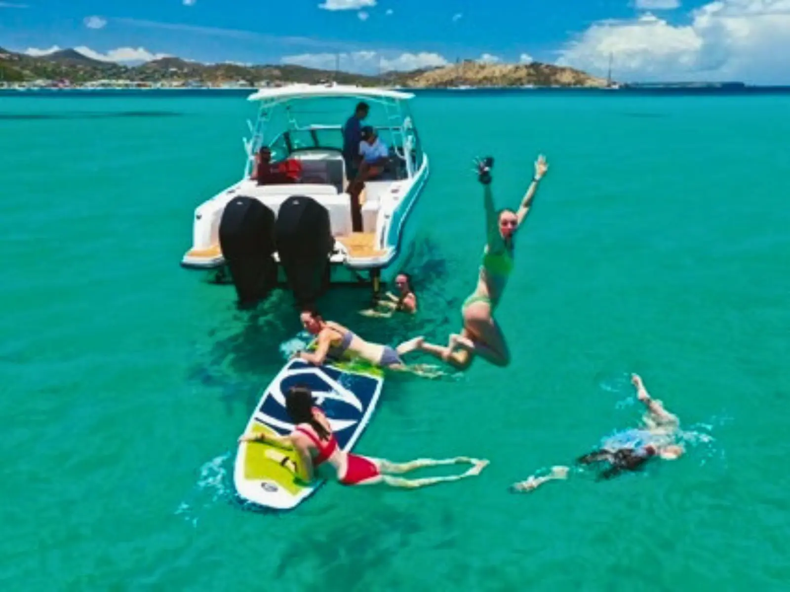 Guests swimming and paddleboarding behind private boat in St Martin