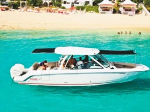 Motorboat anchored near sandy Caribbean beach with passengers onboard