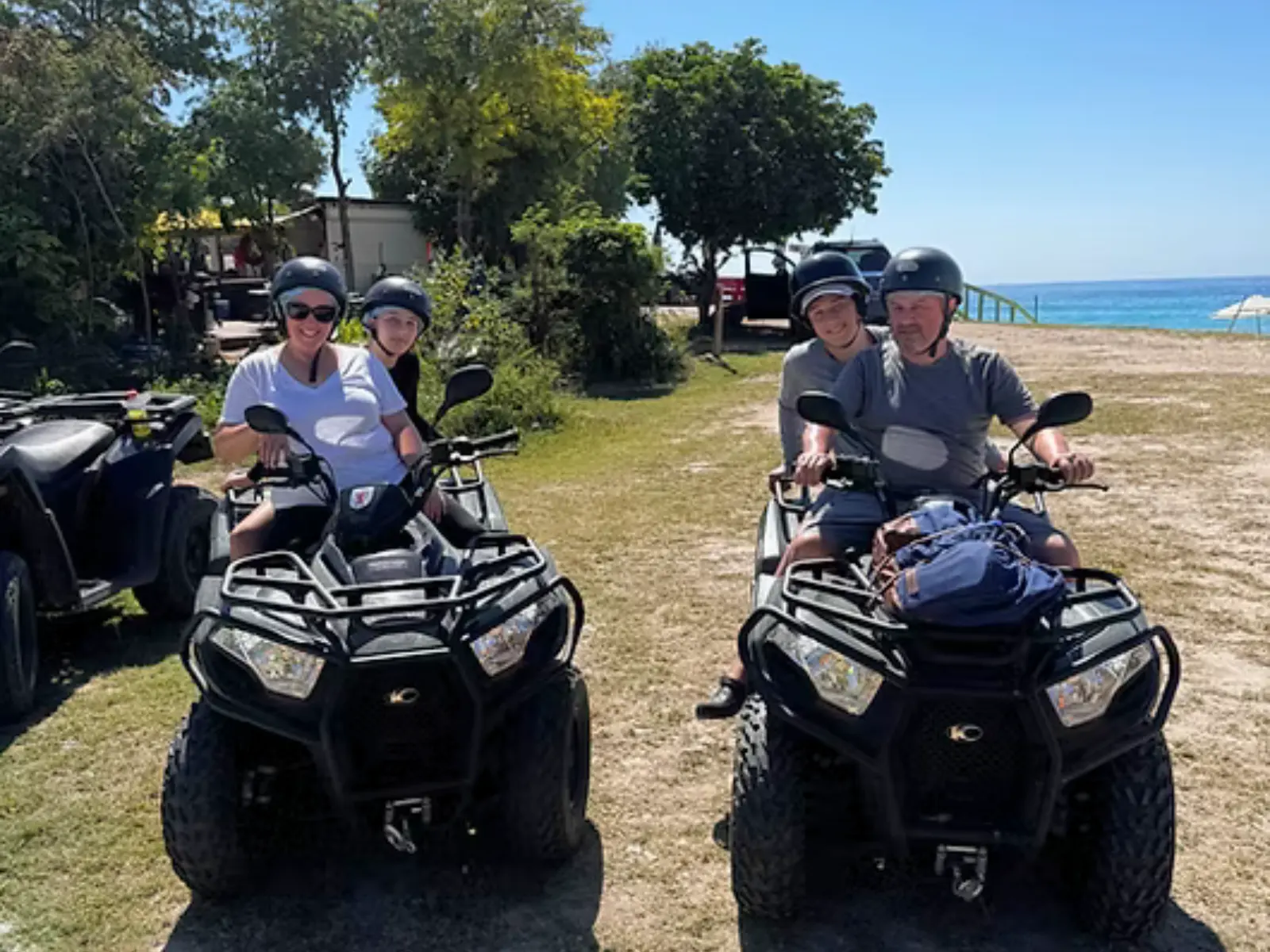 Couples wearing helmets seated on ATVs near the beach with ocean views in St Martin