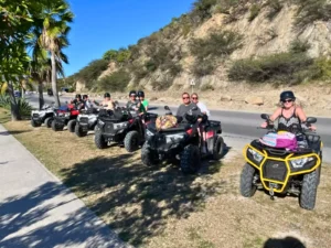 Group of riders on ATVs lined up beside a coastal road in St Maarten during a guided quad tour