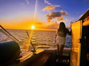 Sunset view from a private catamaran in St Maarten with guest standing on deck at golden hour