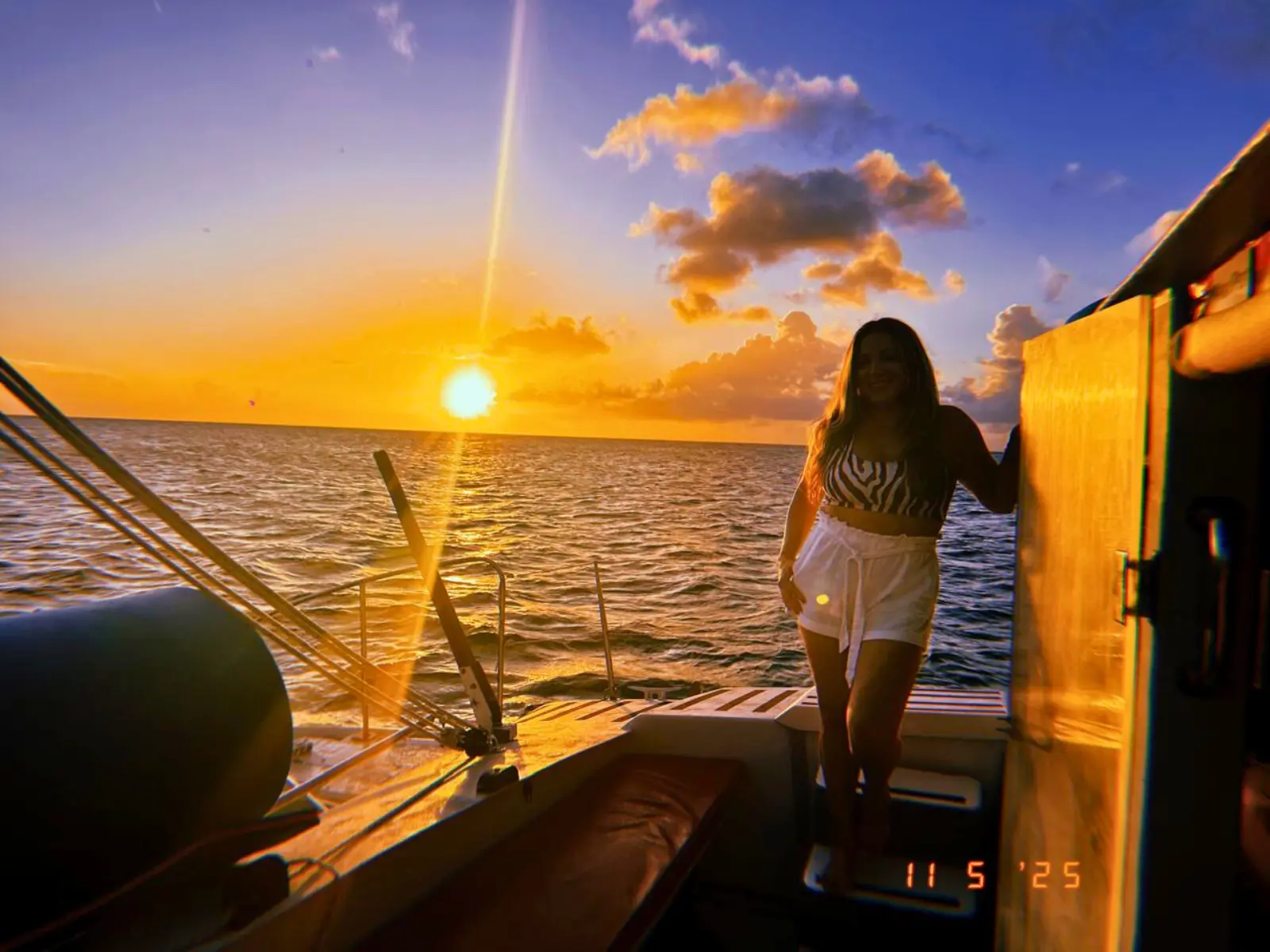 Sunset view from a private catamaran in St Maarten with guest standing on deck at golden hour