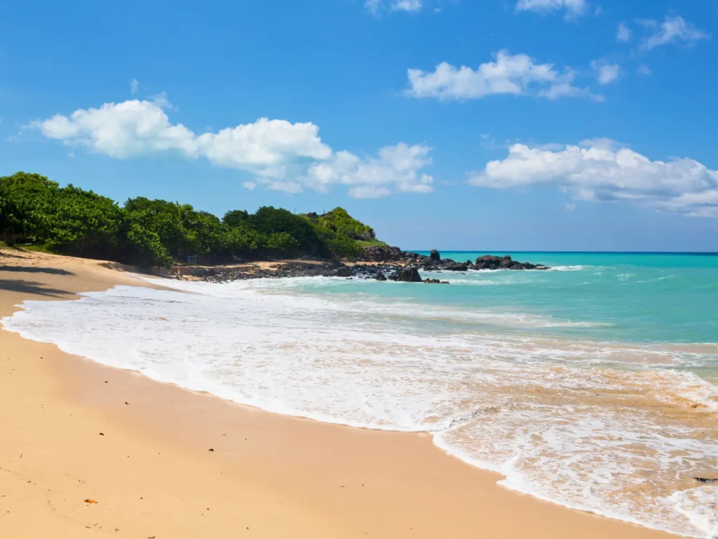 Quiet sandy beach at Happy Bay in St Martin with turquoise water and lush green hillside