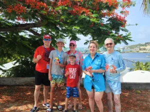 Smiling family group posing under flowering tropical trees with bay views in St Maarten