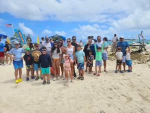Large group of adults and children gathered on a sandy beach during a guided island tour in St Maarten