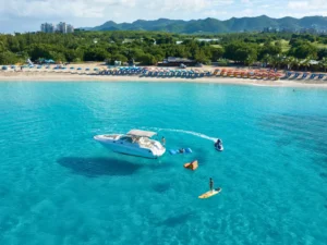 Drone view of luxury mini yacht anchored near St Maarten beach with paddleboard and jet ski activity