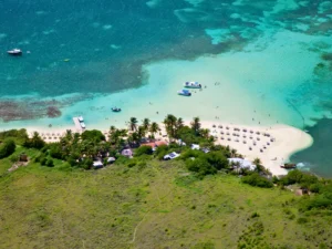 Aerial view of Pinel Island in St Martin with shallow turquoise water, anchored boats, and sandy beach