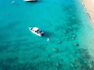 Aerial view of a private motorboat anchored in shallow turquoise waters near a sandy beach in St Martin
