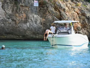 Guest diving from a private motorboat into clear turquoise water near rocky cliffs in St Martin