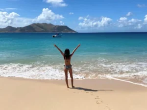 Traveler standing on a sandy beach facing turquoise waters during a private boat charter in St Martin