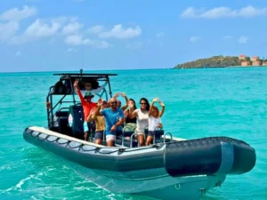 Private RIB speedboat with guests waving while cruising through bright blue waters in St Maarten