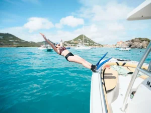 Guest diving off a private speedboat in turquoise water at Grand Case Bay, St Maarten