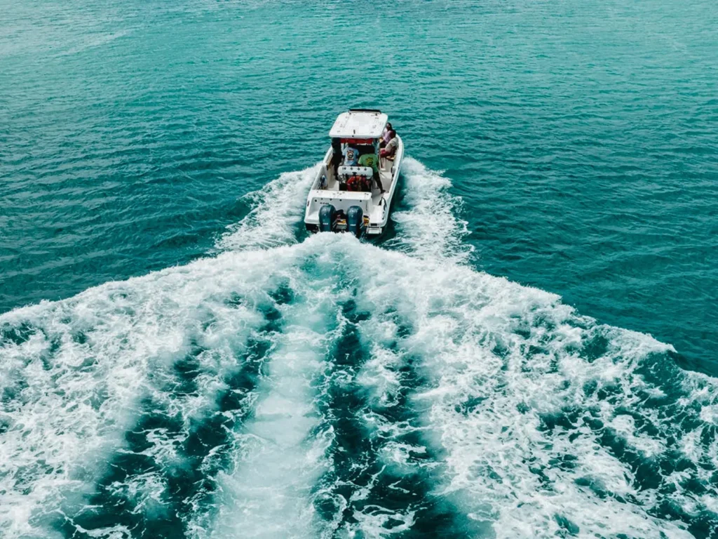 Drone view of a private speedboat leaving a foamy wake on turquoise sea, St Maarten