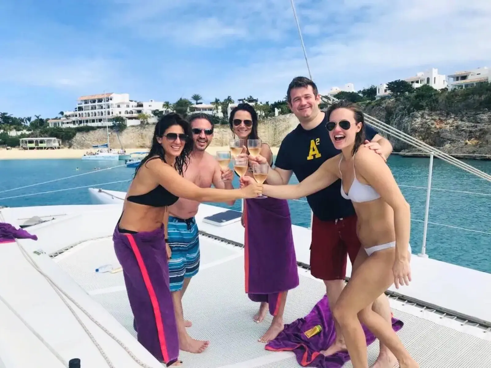 Group of friends toasting drinks aboard a trimaran during a sailing tour in St Maarten