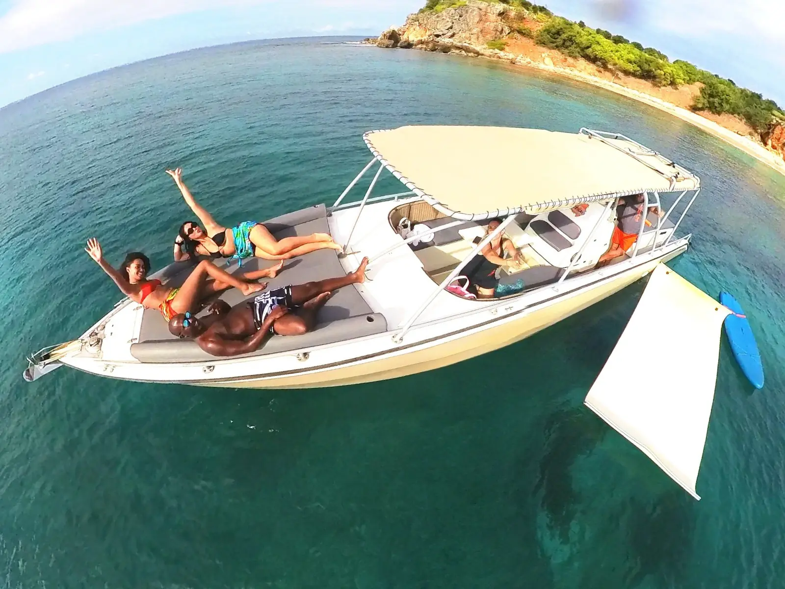 Guests lounging on forward sunbed of a private powerboat charter in calm Caribbean waters