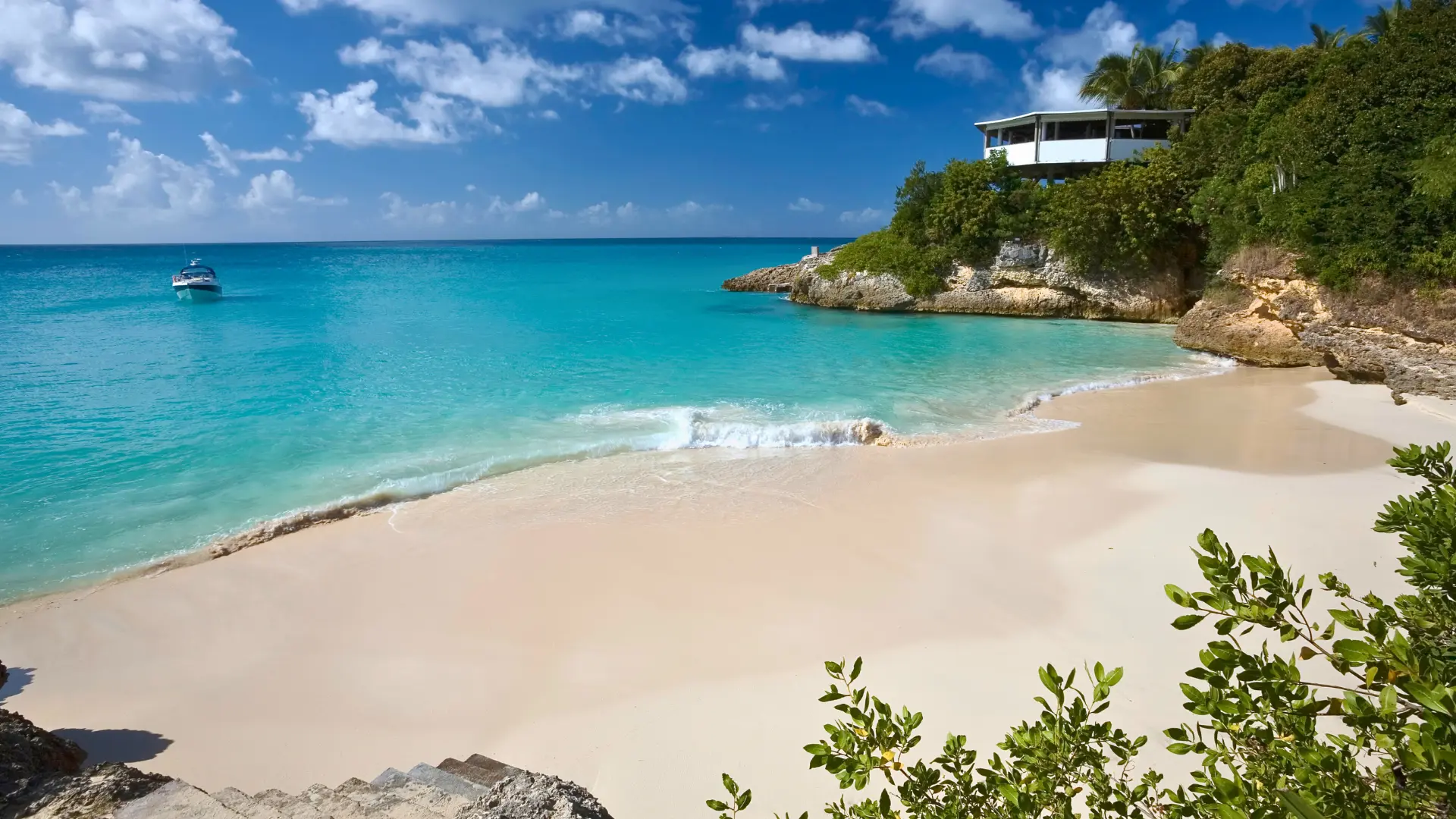 Small private boat anchored in a quiet Anguilla bay with white sand beach and clear water