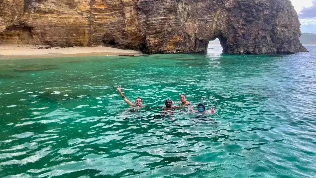 Guests swimming in clear water near cliffs in Baie Rouge, St Martin during private boat trip