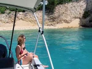 Guest sitting on a private boat near a secluded beach with clear turquoise water in Saint Martin