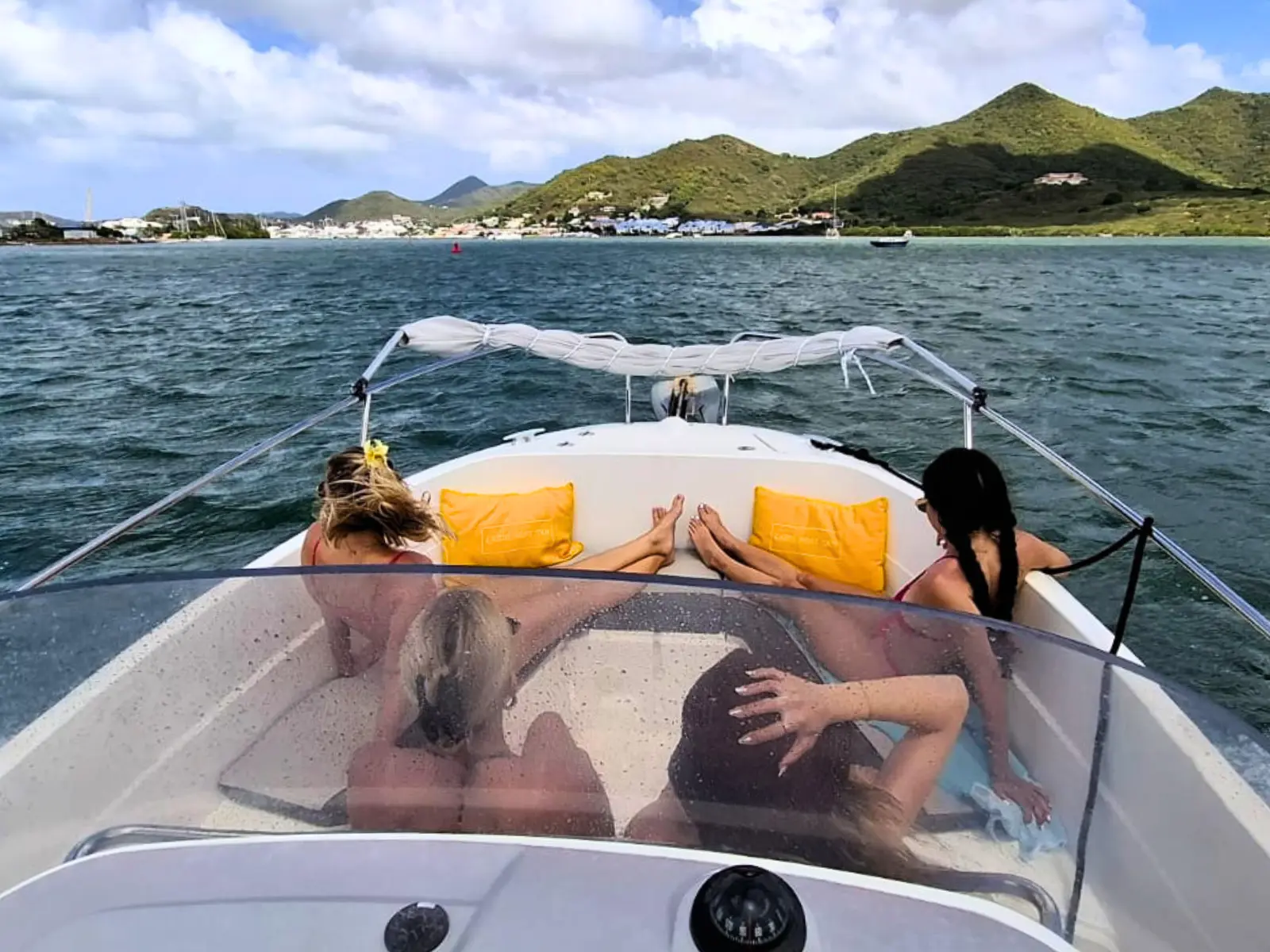 Guests relaxing on the front deck of a private boat cruising along Saint Martin coastline