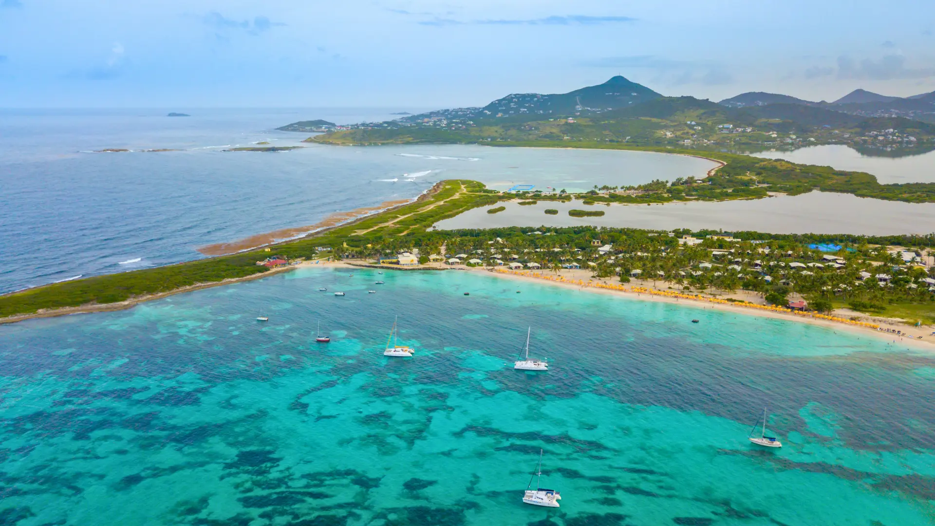 Aerial view of St Martin coastline with turquoise water and boats anchored near shore