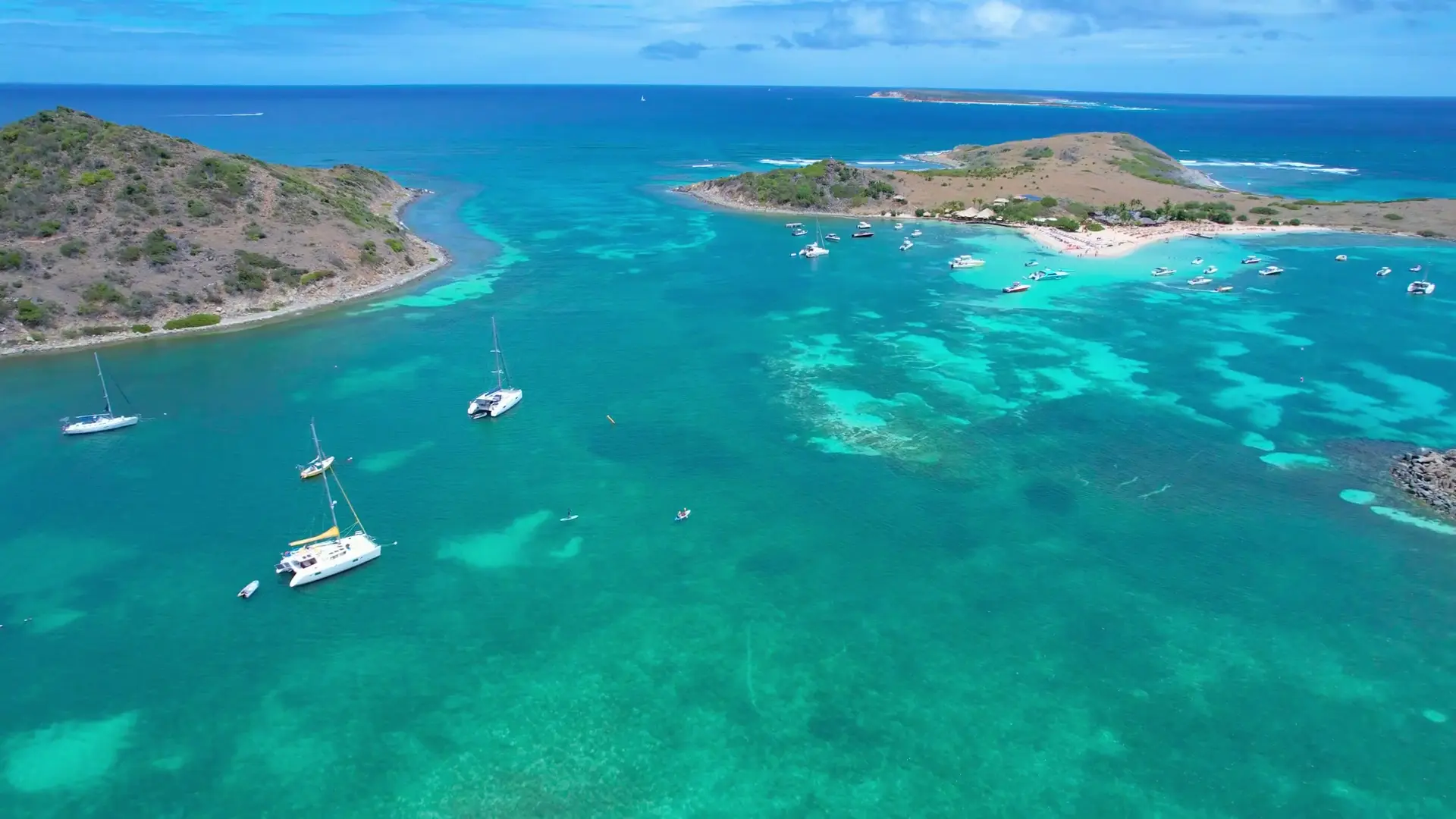 Aerial view of secluded bay in Pinel with private boats and turquoise water