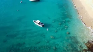 Private boat anchored in calm turquoise bay near beach in St Martin