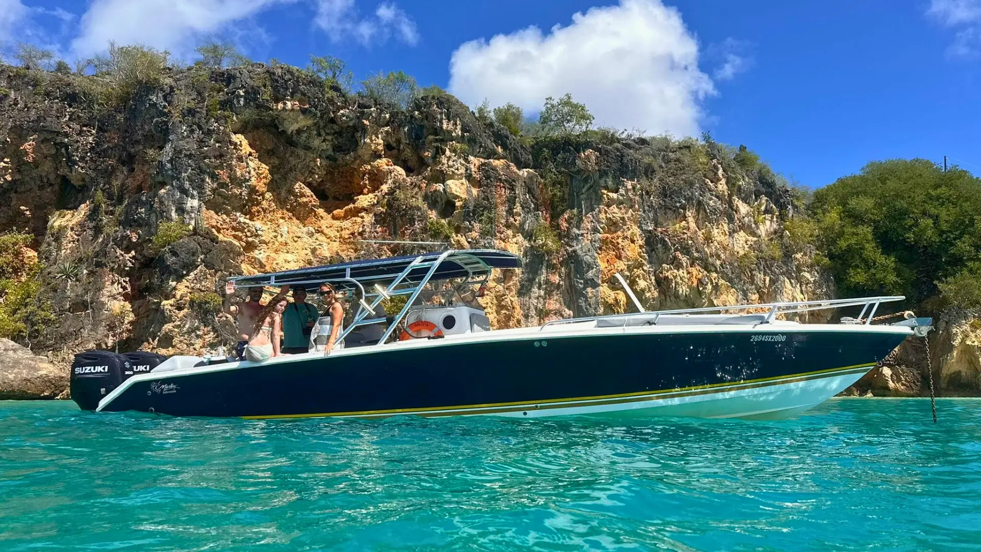 Group on private motorboat near rocky coastline in St Martin